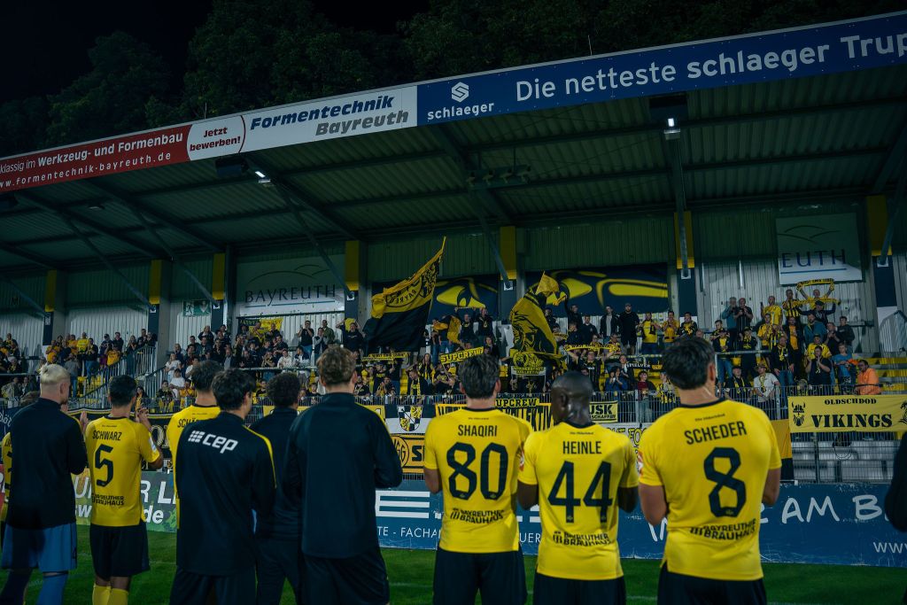 Die Mannschaft der SpVgg Bayreuth nach dem Sieg gegen Aubstadt vor der Fankurve